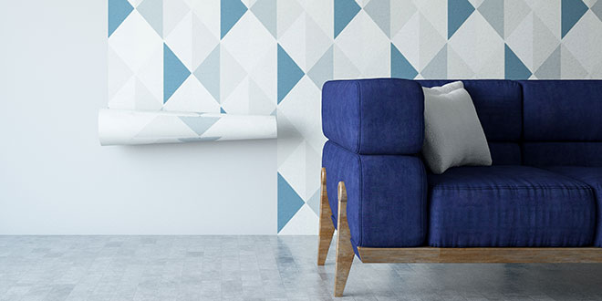 A blue sofa in front of geometric wallpaper being applied