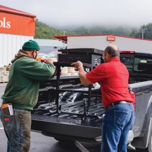 Hardware store employees helping load a grill onto a customer's truck