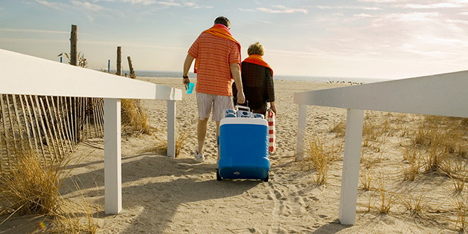 a retired couple pulling a cooler onto a beach